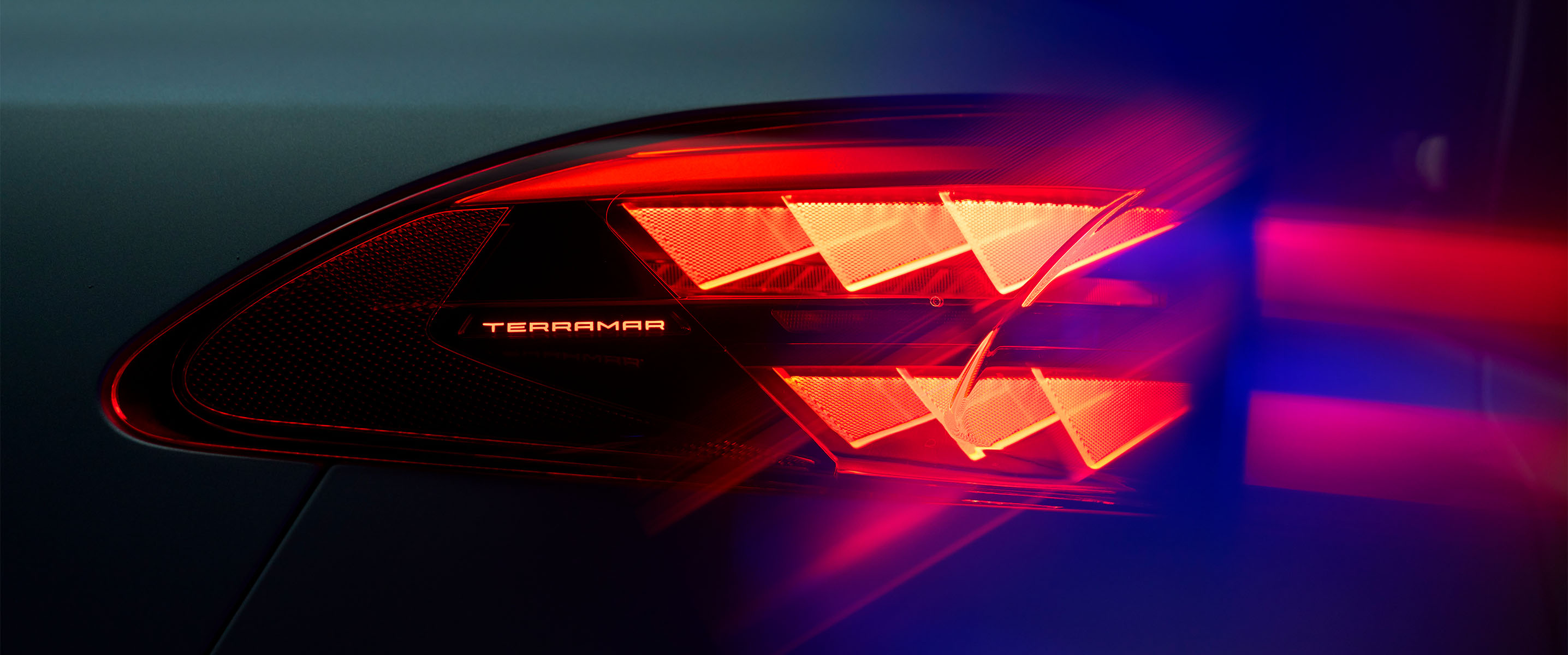 cupra terramar close-up of rear taillight with illuminated model name, showing distinctive red triangular light pattern against dark background