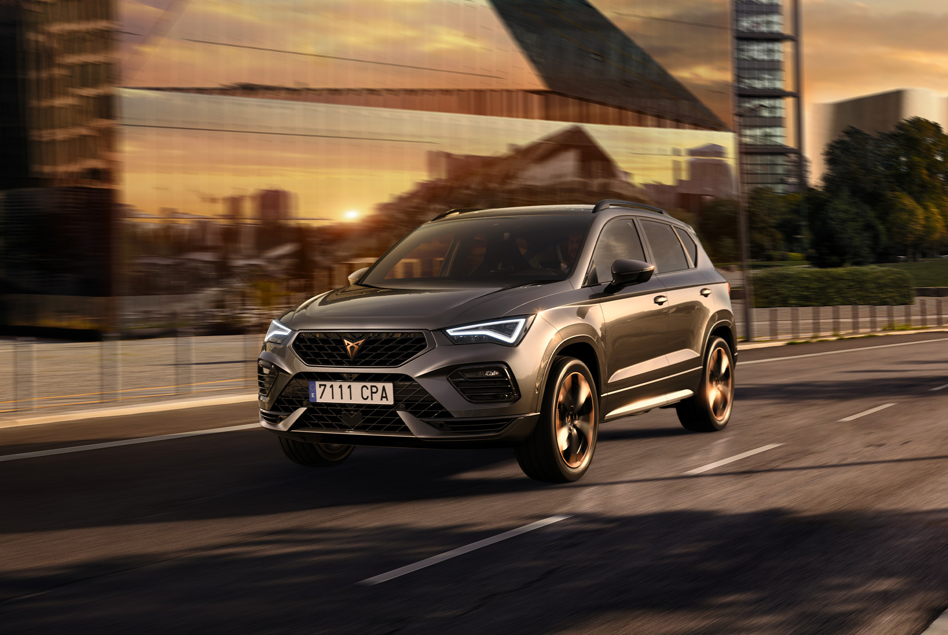 CUPRA Ateca SUV driving on a city road at sunset. The SUV is available with engines in 150hp, offering less emissions and fuel consumption.