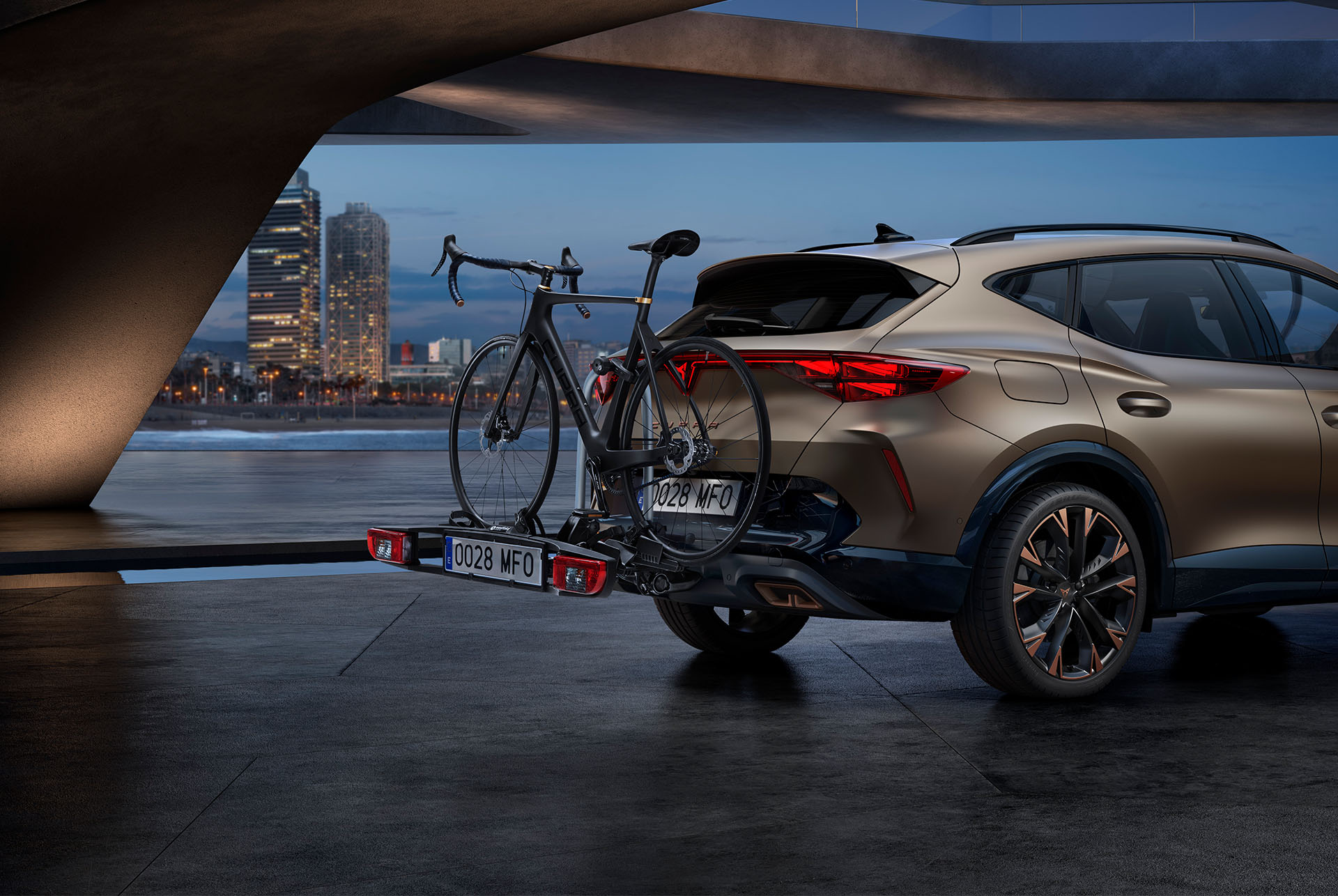 New century bronze CUPRA Formentor rear and towing bike rack car accessory, city skyline in the background.