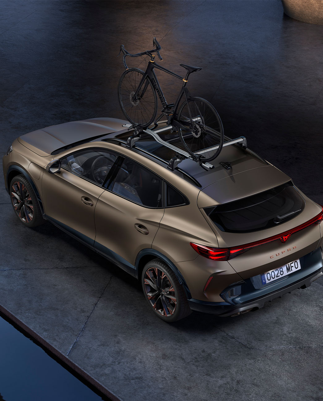 Bird’s eye view of new century bronze matt CUPRA Formentor with car bike rack accessory, car parked on concrete at dusk.