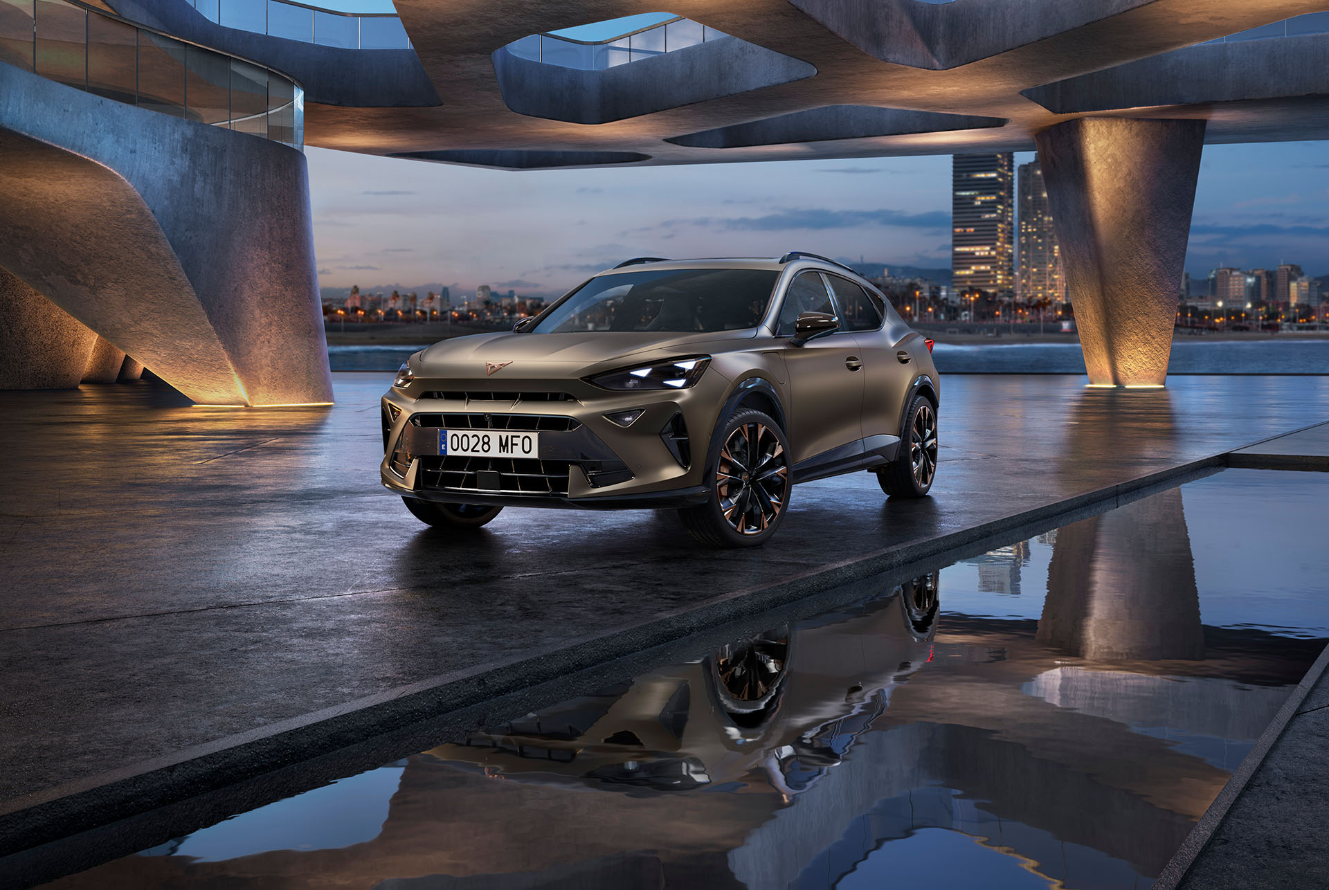 New CUPRA Formentor technology. The car with copper accent wheels is parked under a curved concrete structure near a reflective water surface, with a twilight cityscape in the background featuring illuminated skyscrapers.