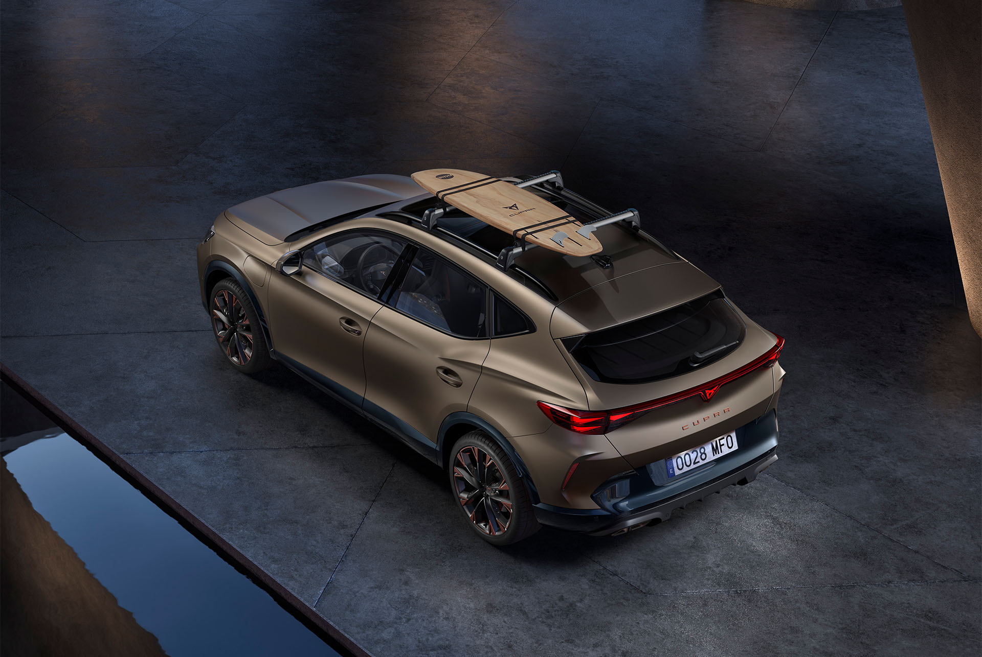 Bird’s eye view of new century bronze matt CUPRA Formentor with car roof surfboard rack accessory, car parked on concrete.