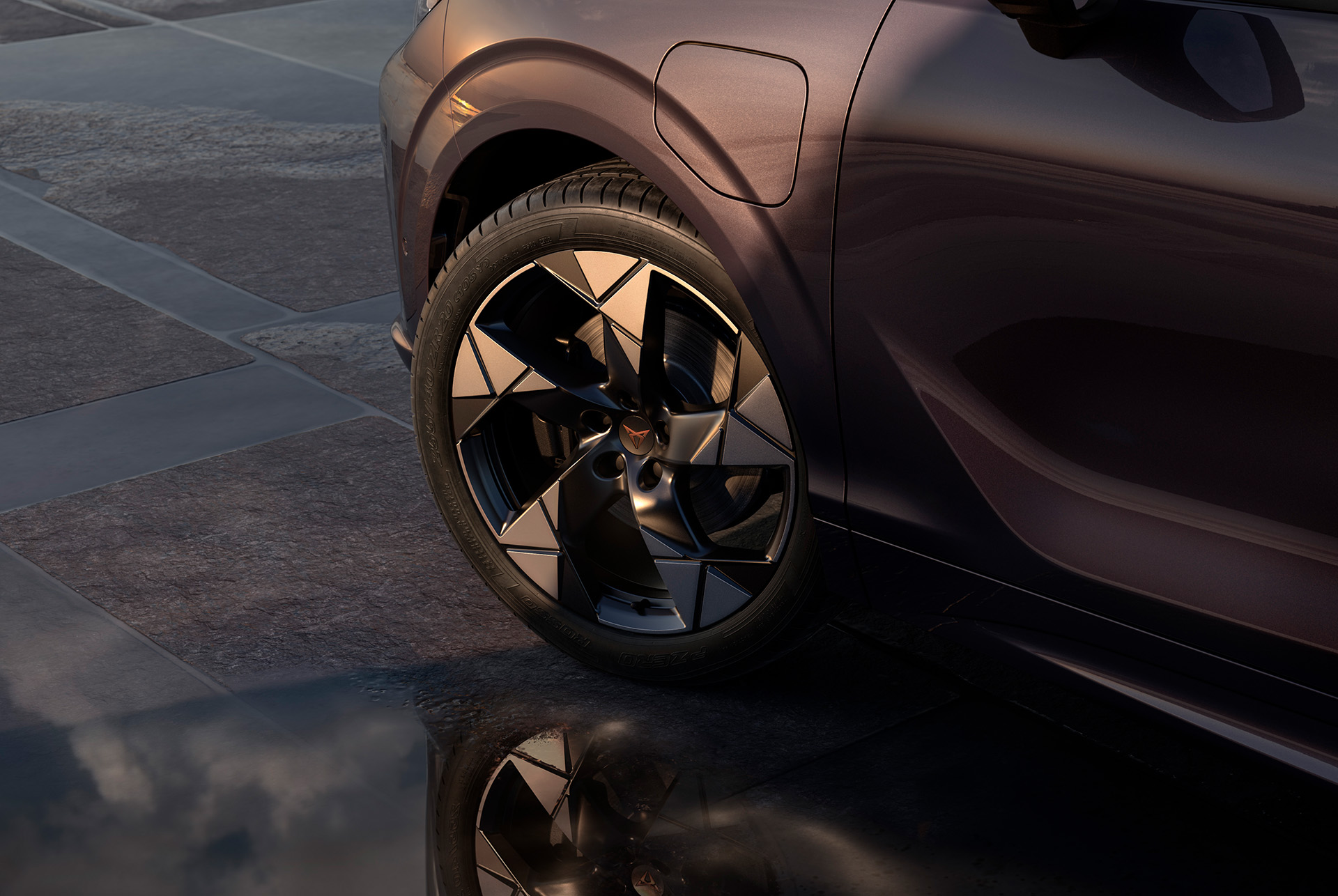 20 inch gravity alloy wheel on the new cupra terramar, in black with copper accents. Background includes a tiled pavement and part of the car's glossy, dark body.