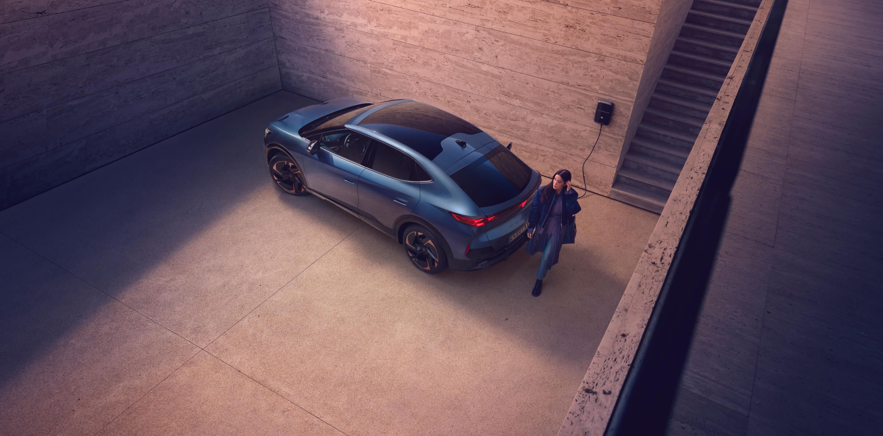 electric suv plugged into a wallbox in a minimalist concrete driveway, driver out of car, showcasing sleek automotive design and home ev charging station